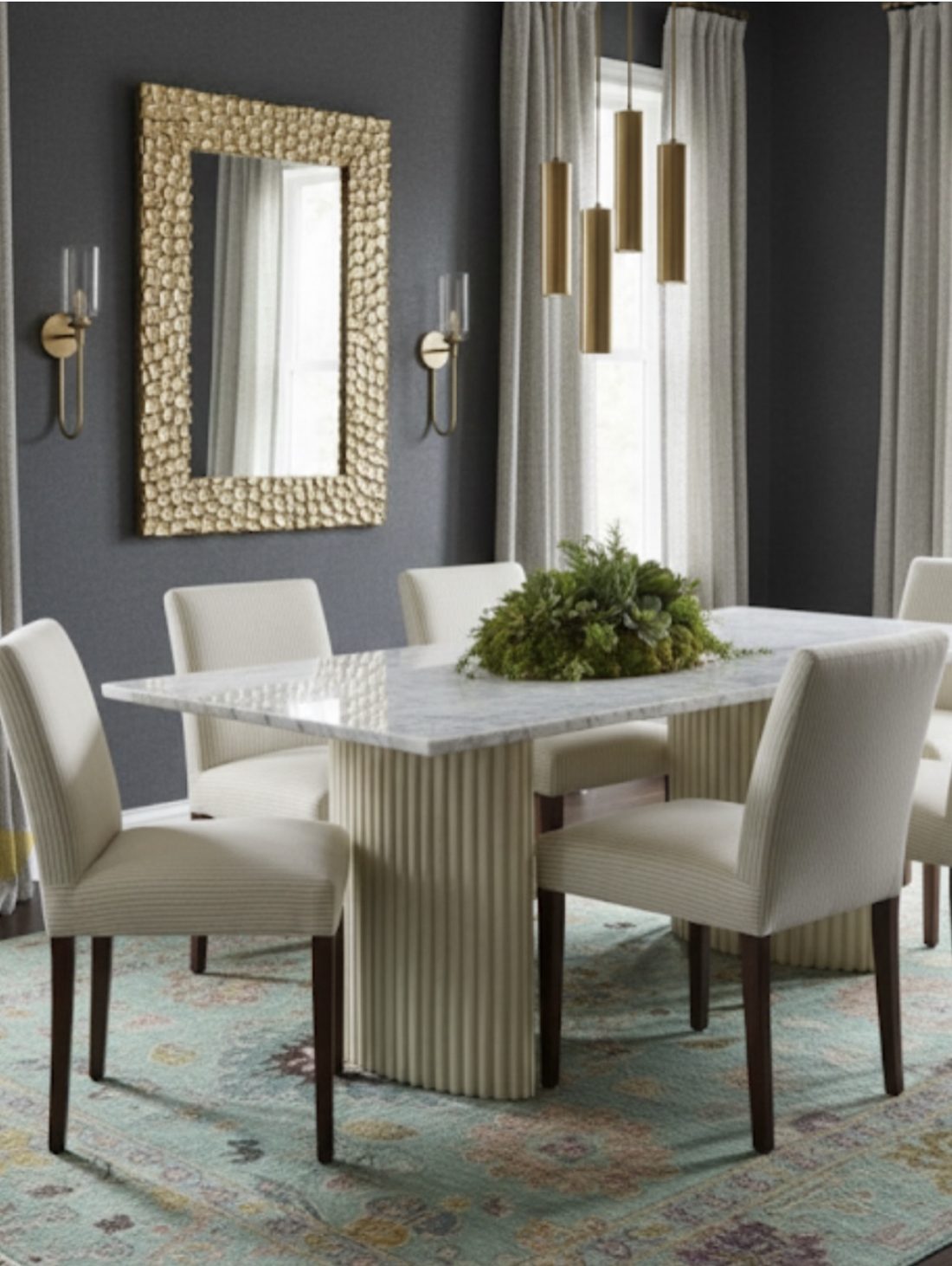 Dramatic dining room with charcoal walls, gold textured mirror, marble table and brass pendants