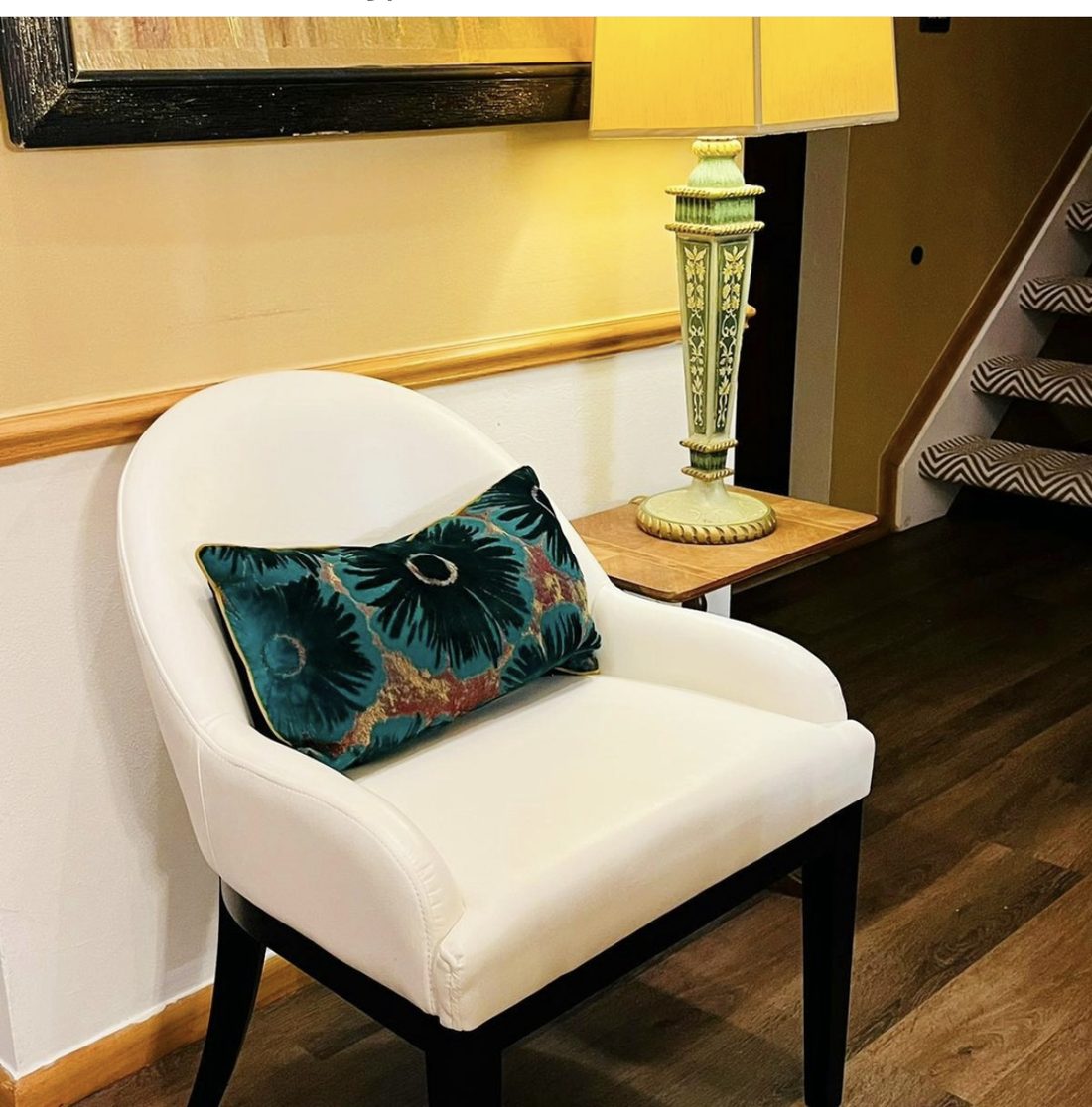 Entry seating vignette with cream chair, teal velvet pillow, and vintage green lamp
